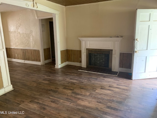 unfurnished living room featuring wood walls, ornamental molding, and dark hardwood / wood-style flooring