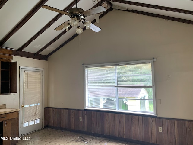 interior space with vaulted ceiling with beams, wood walls, dark brown cabinetry, and ceiling fan