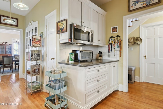 600 N Beach Blvd, Bay Saint Louis, MS 39520 - kitchen featuring stainless steel microwave, light wood-style flooring, tasteful backsplash, and white cabinets