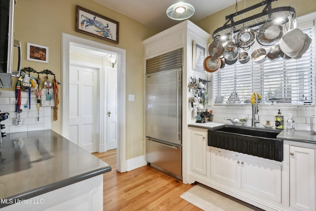 600 N Beach Blvd, Bay Saint Louis, MS 39520 - kitchen with built in fridge, tasteful backsplash, white cabinets, light wood finished floors, and stainless steel countertops