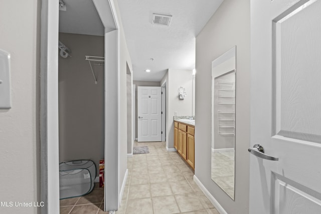 bathroom featuring visible vents, tile patterned flooring, vanity, baseboards, and a spacious closet