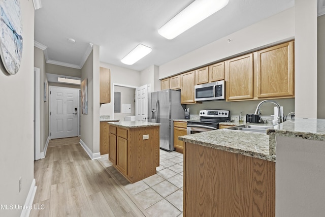 kitchen with crown molding, a center island, light stone counters, a sink, and stainless steel appliances