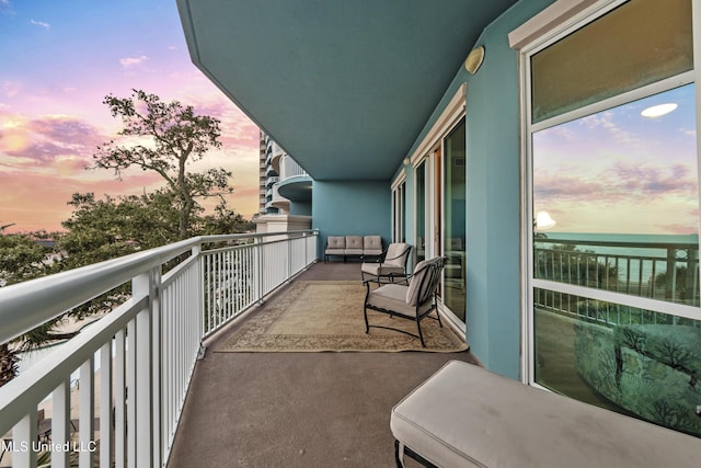 balcony at dusk featuring a water view