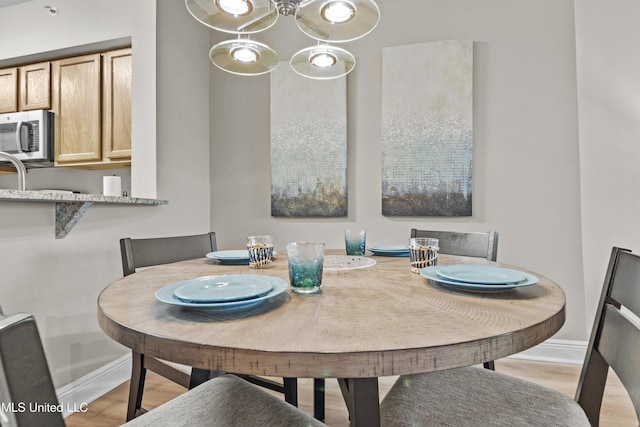 dining room featuring baseboards, light wood-style floors, and an inviting chandelier