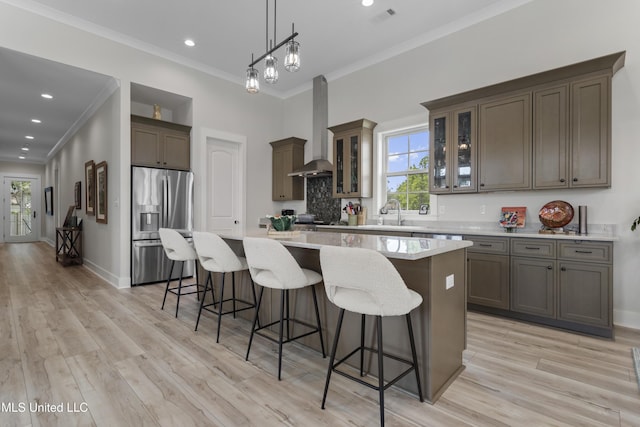 435 Bills Ave, Ocean Springs, MS 39564 - kitchen featuring stainless steel refrigerator with ice dispenser, wall chimney range hood, a center island, a kitchen bar, and ornamental molding