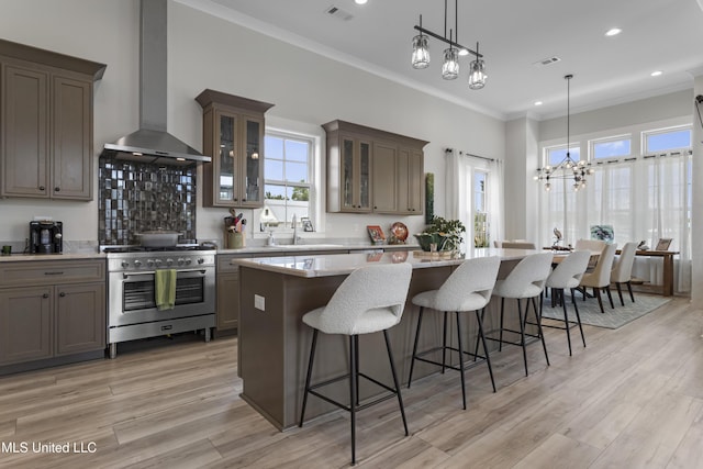435 Bills Ave, Ocean Springs, MS 39564 - kitchen with wall chimney exhaust hood, stainless steel range, a sink, a kitchen bar, and a center island