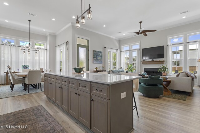 435 Bills Ave, Ocean Springs, MS 39564 - kitchen with a fireplace, a chandelier, a kitchen island, ornamental molding, and light wood-style floors