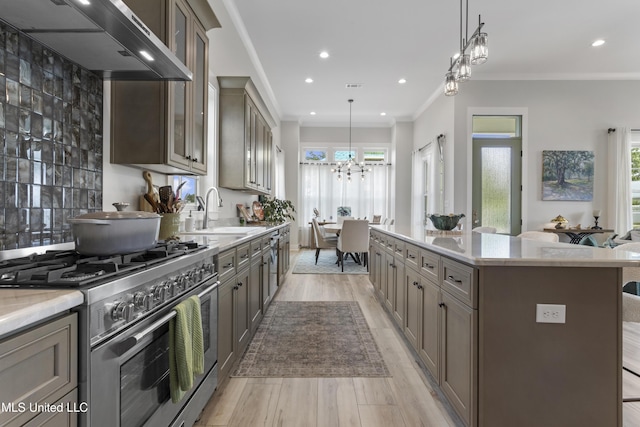 435 Bills Ave, Ocean Springs, MS 39564 - kitchen featuring high end stainless steel range, a sink, wall chimney range hood, light wood-type flooring, and a kitchen island