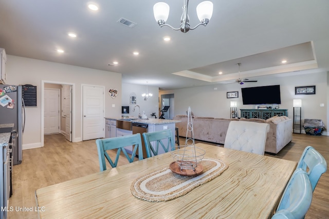 11458 Leann Ct, Ocean Springs, MS 39564 - dining room featuring a chandelier, a ceiling fan, light wood-style flooring, recessed lighting, and a tray ceiling