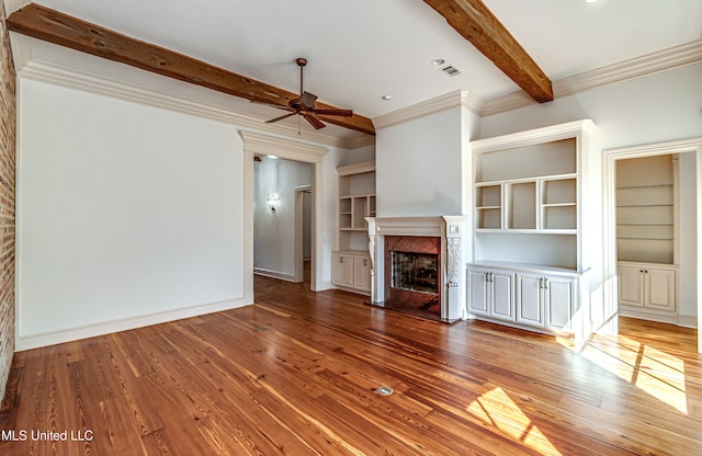 unfurnished living room with hardwood / wood-style flooring, beamed ceiling, ornamental molding, and a high end fireplace