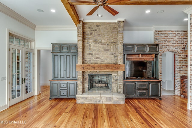 unfurnished living room featuring beam ceiling, ceiling fan, light wood-type flooring, a fireplace, and crown molding