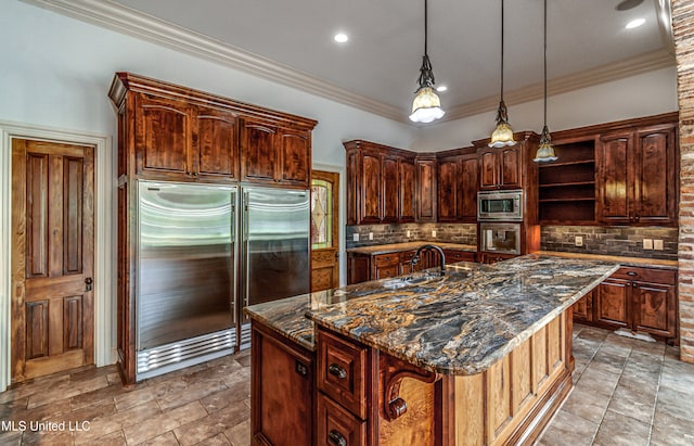 kitchen with built in appliances, a kitchen island with sink, and dark stone countertops