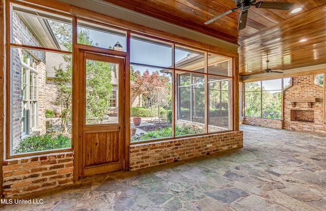 unfurnished sunroom featuring ceiling fan, wooden ceiling, and plenty of natural light