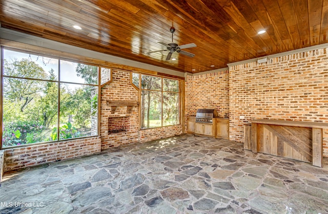 unfurnished living room featuring wood ceiling, brick wall, and a wealth of natural light