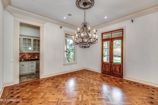 unfurnished dining area featuring crown molding, light parquet floors, an inviting chandelier, and french doors