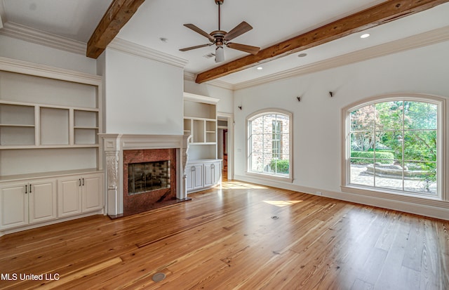 unfurnished living room with beam ceiling, light hardwood / wood-style flooring, crown molding, a fireplace, and ceiling fan