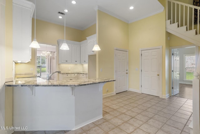 504 Carlisle Cir, Madison, MS 39110 - kitchen featuring a high ceiling, a peninsula, a breakfast bar area, light stone countertops, and tasteful backsplash