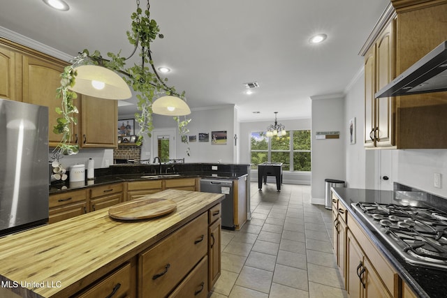 8185 Ridgewood Dr, Kiln, MS 39556 - kitchen featuring wall chimney exhaust hood, stainless steel appliances, a sink, butcher block counters, and ornamental molding