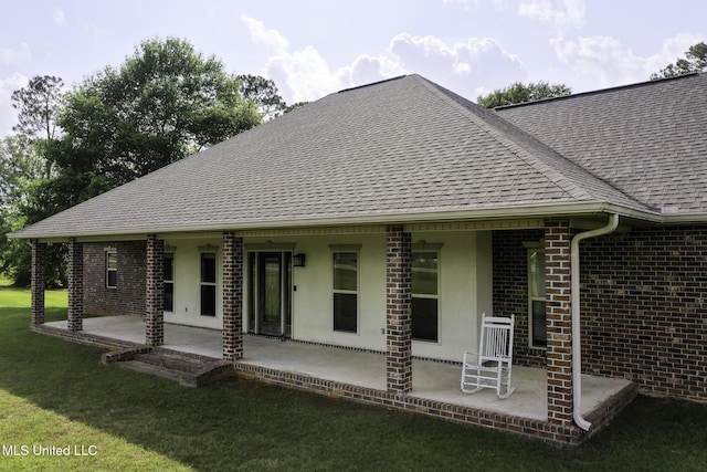 8185 Ridgewood Dr, Kiln, MS 39556 - rear view of property featuring a shingled roof, a patio area, brick siding, and a yard