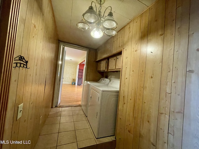 1103 N Yale St, Cleveland, MS 38732 - laundry area featuring cabinet space, wood walls, washer and clothes dryer, light tile patterned flooring, and a chandelier