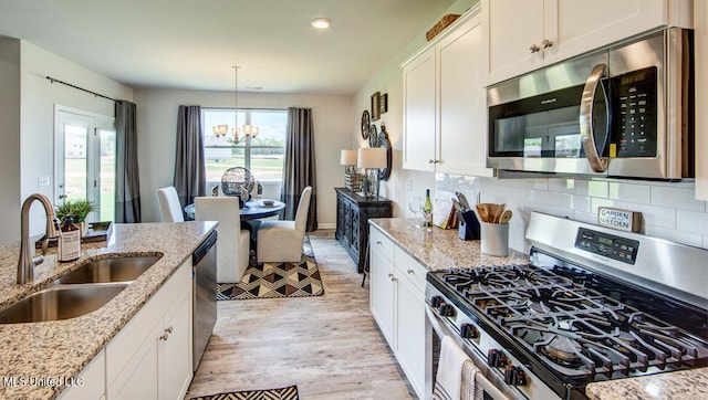 kitchen featuring light hardwood / wood-style floors, sink, light stone countertops, and stainless steel appliances