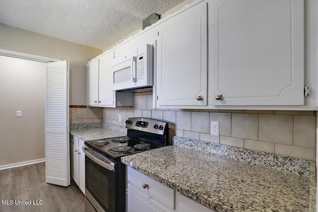 kitchen with electric stove, backsplash, wood-type flooring, a textured ceiling, and white cabinets