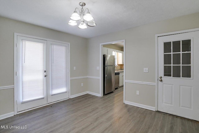 doorway featuring a textured ceiling, french doors, a chandelier, and light wood-type flooring