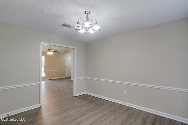 empty room with a notable chandelier, a textured ceiling, and dark hardwood / wood-style flooring