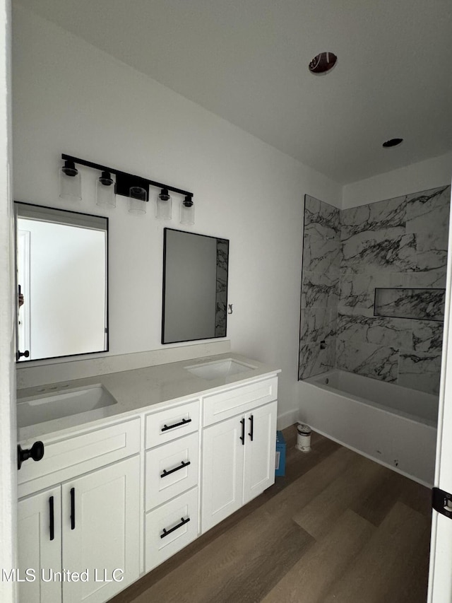 bathroom featuring wood-type flooring, tiled shower / bath combo, and vanity