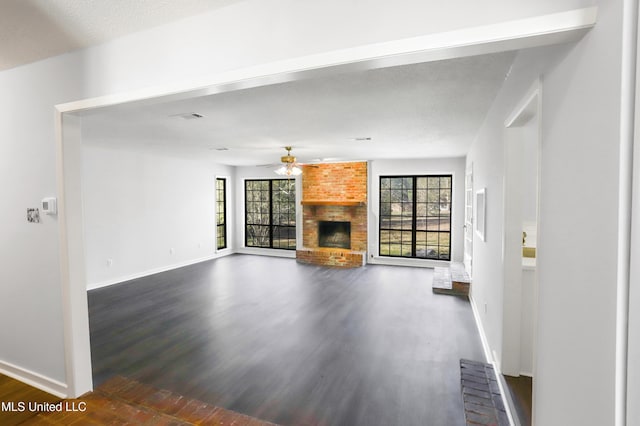 unfurnished living room featuring ceiling fan, wood-type flooring, and a brick fireplace