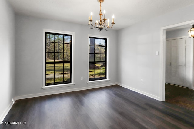 unfurnished dining area with a wealth of natural light, dark hardwood / wood-style floors, and a notable chandelier