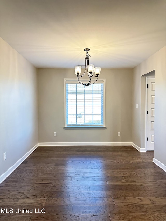 spare room with a chandelier and dark hardwood / wood-style floors