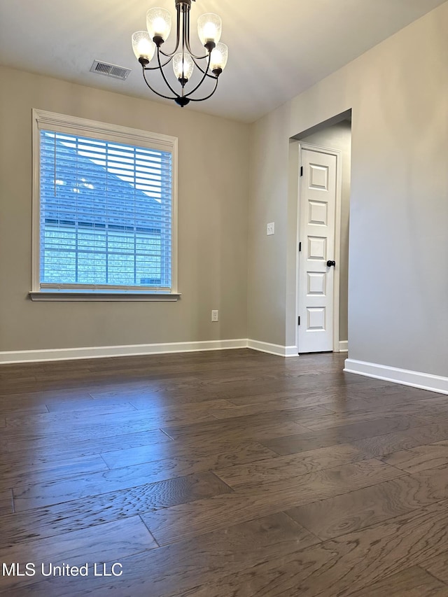 spare room with dark hardwood / wood-style flooring and a notable chandelier