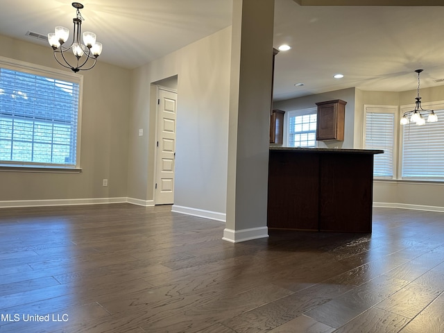 empty room featuring dark hardwood / wood-style flooring, plenty of natural light, and a notable chandelier