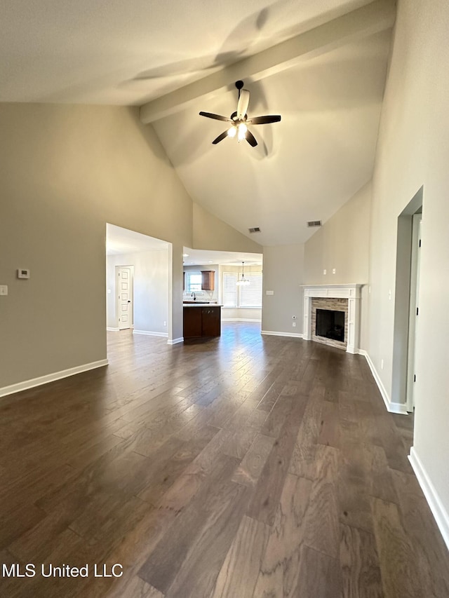 unfurnished living room featuring beamed ceiling, dark hardwood / wood-style floors, ceiling fan, and a tiled fireplace