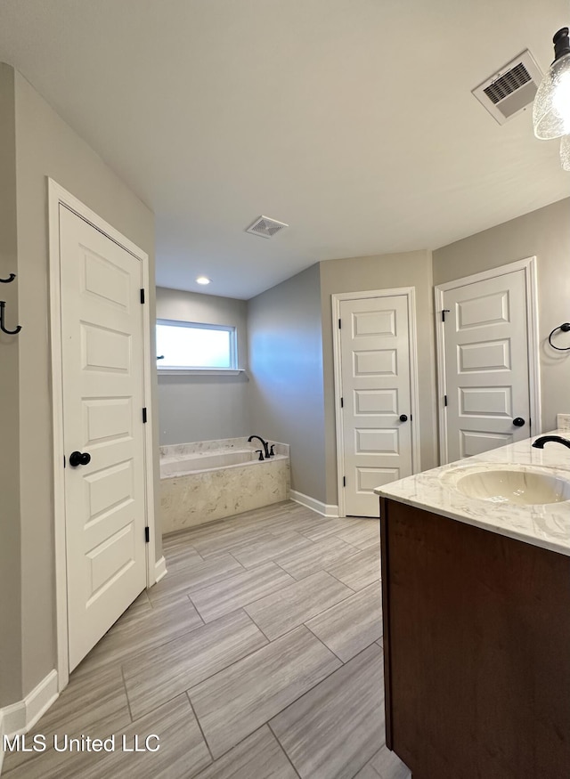 bathroom featuring vanity and tiled tub