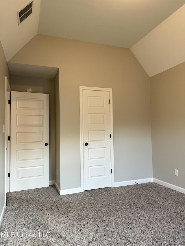 unfurnished bedroom featuring carpet, a closet, and vaulted ceiling