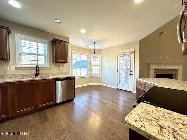 kitchen featuring pendant lighting, dishwasher, a tile fireplace, sink, and dark hardwood / wood-style flooring