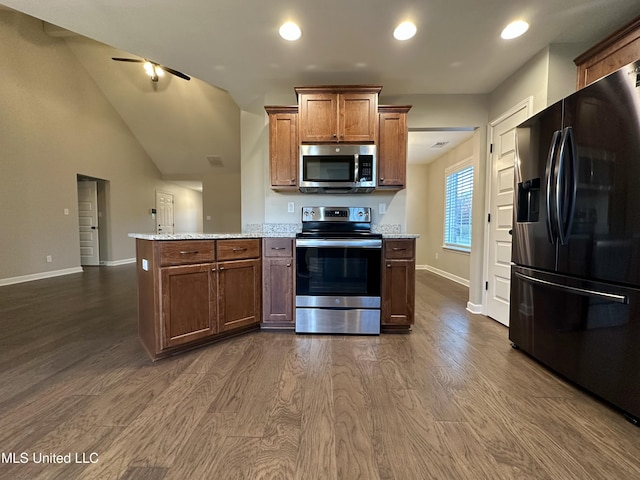 kitchen with light stone countertops, dark hardwood / wood-style flooring, stainless steel appliances, and high vaulted ceiling