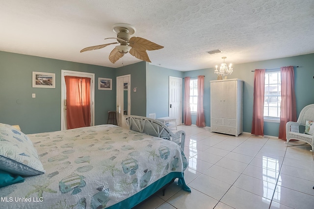 bedroom featuring light tile patterned flooring, a closet, ceiling fan with notable chandelier, and a textured ceiling