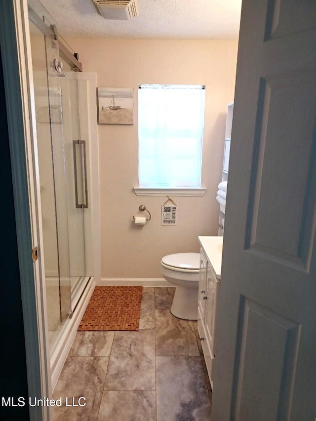 bathroom featuring walk in shower, vanity, toilet, and a textured ceiling