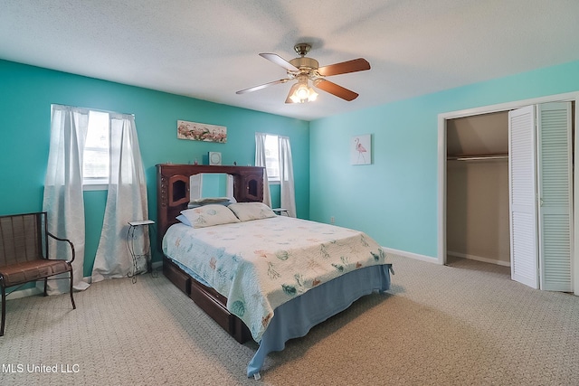 bedroom featuring light colored carpet, a textured ceiling, ceiling fan, and a closet