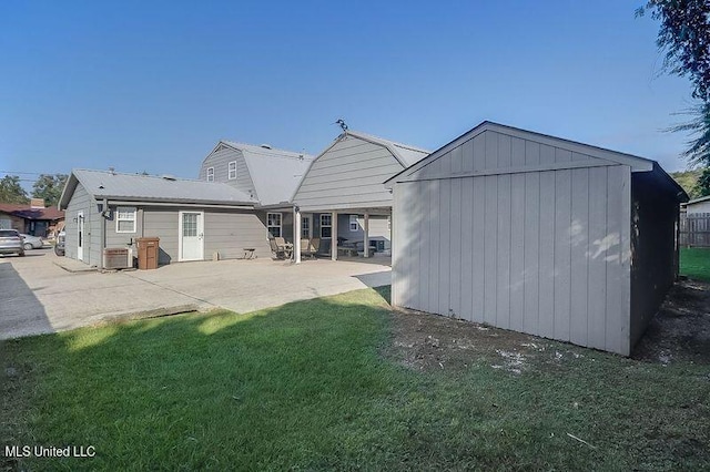 back of property featuring a yard, a patio area, and an outdoor structure