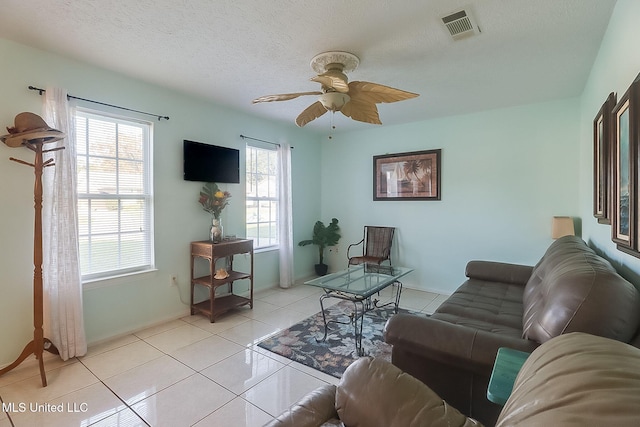 living room featuring ceiling fan, a textured ceiling, and light tile patterned flooring