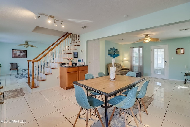 tiled dining space with a textured ceiling and ceiling fan