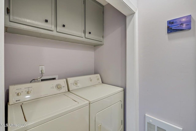 clothes washing area with separate washer and dryer and cabinet space