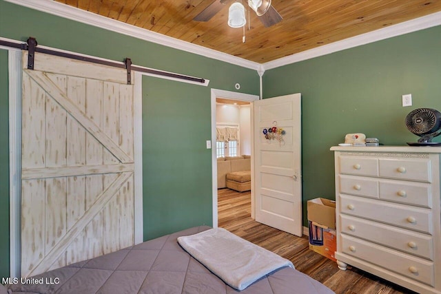 bedroom with a barn door, a ceiling fan, crown molding, wood finished floors, and wooden ceiling