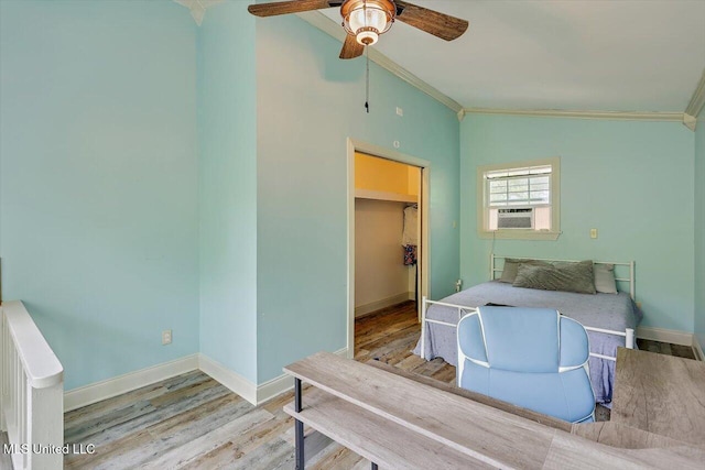 bedroom with wood finished floors, a closet, a walk in closet, baseboards, and ornamental molding