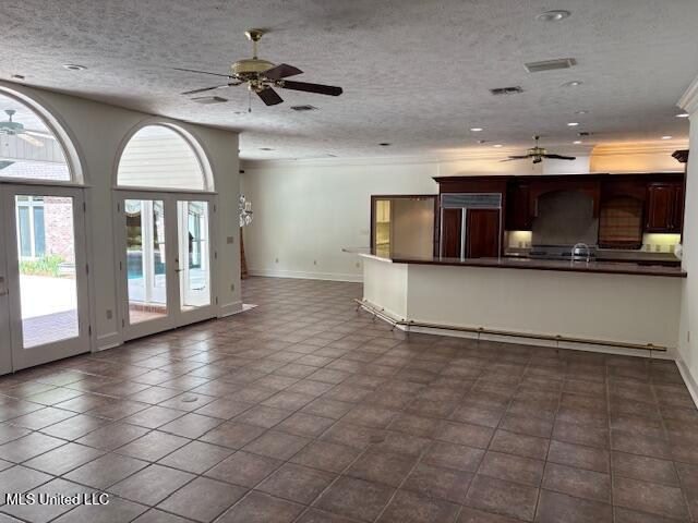 unfurnished living room with a ceiling fan, a textured ceiling, a sink, baseboards, and ornamental molding