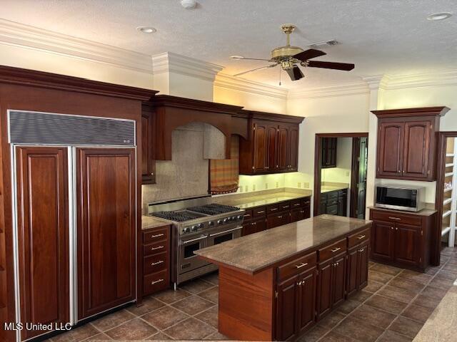 kitchen with a center island, a ceiling fan, high end appliances, tasteful backsplash, and dark tile patterned floors